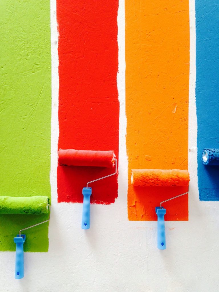 quatre rouleaux de peinture orange, vert, bleu et rouge